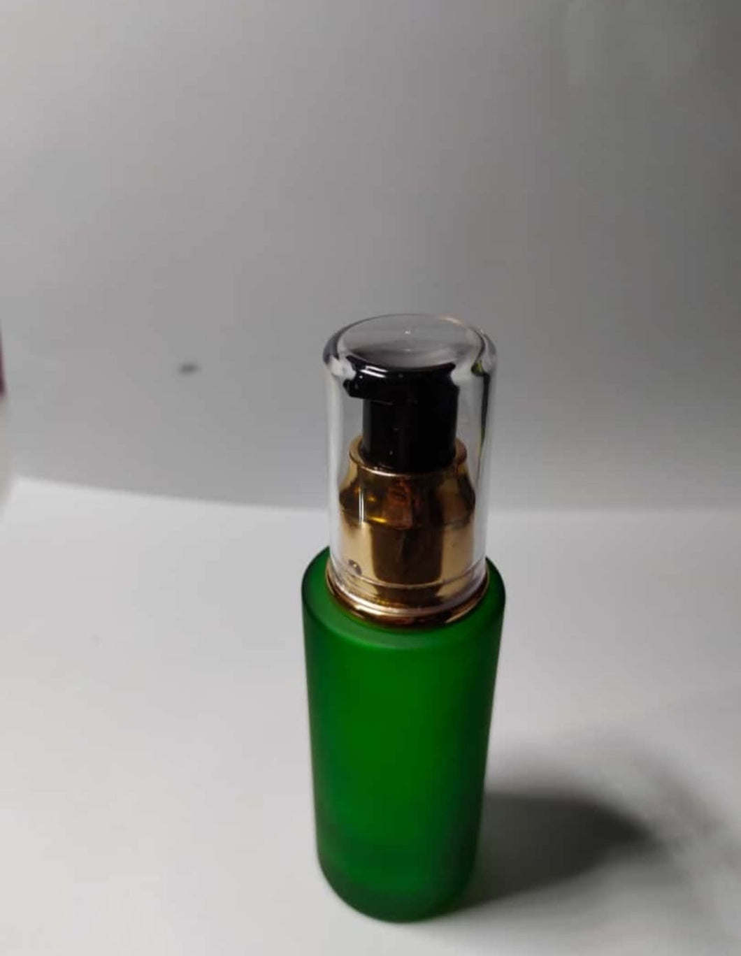 CP7246 50ml. green glass flat neck bottle with golden black cream pump